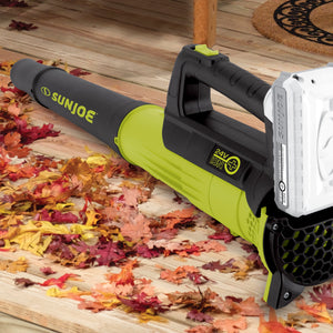 Sun Joe 24-volt cordless turbine leaf blower laying in leaves on a hardwood floor.
