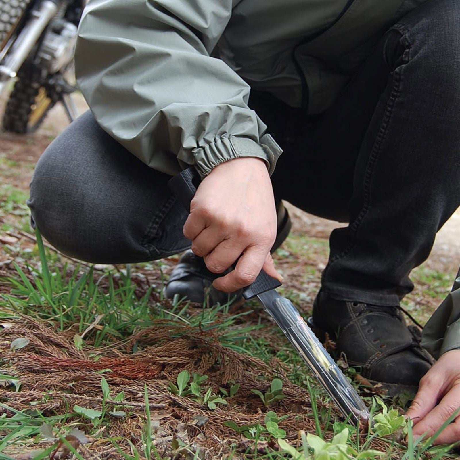 Person using the Nisaku Limited Yamakatana Edition 7.5-inch Japanese Stainless Steel Knife to get a weed out of the ground.
