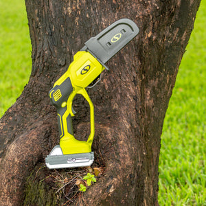 Sun Joe Cordless Handheld Chainsaw with its chain cover on, resting outside on a tree.