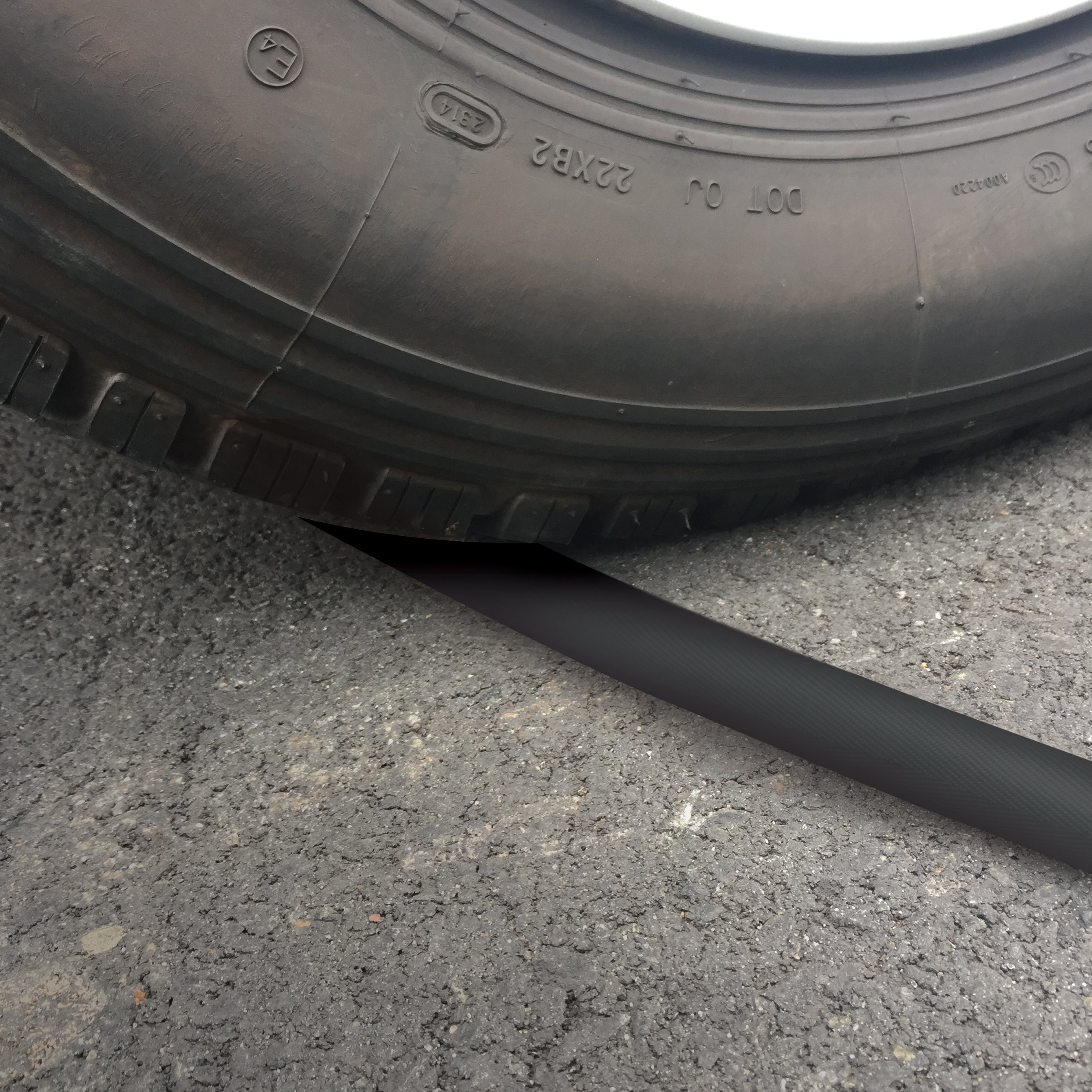 Car running over the Aqua Joe 75-foot non-expanding black fiberjacket hose.
