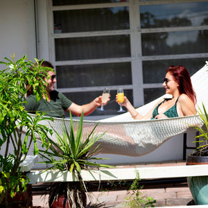 Couple laying in the Bliss Hammocks 55-inch Wide 2-Person Weekender Deluxe Hammock while having drinks.