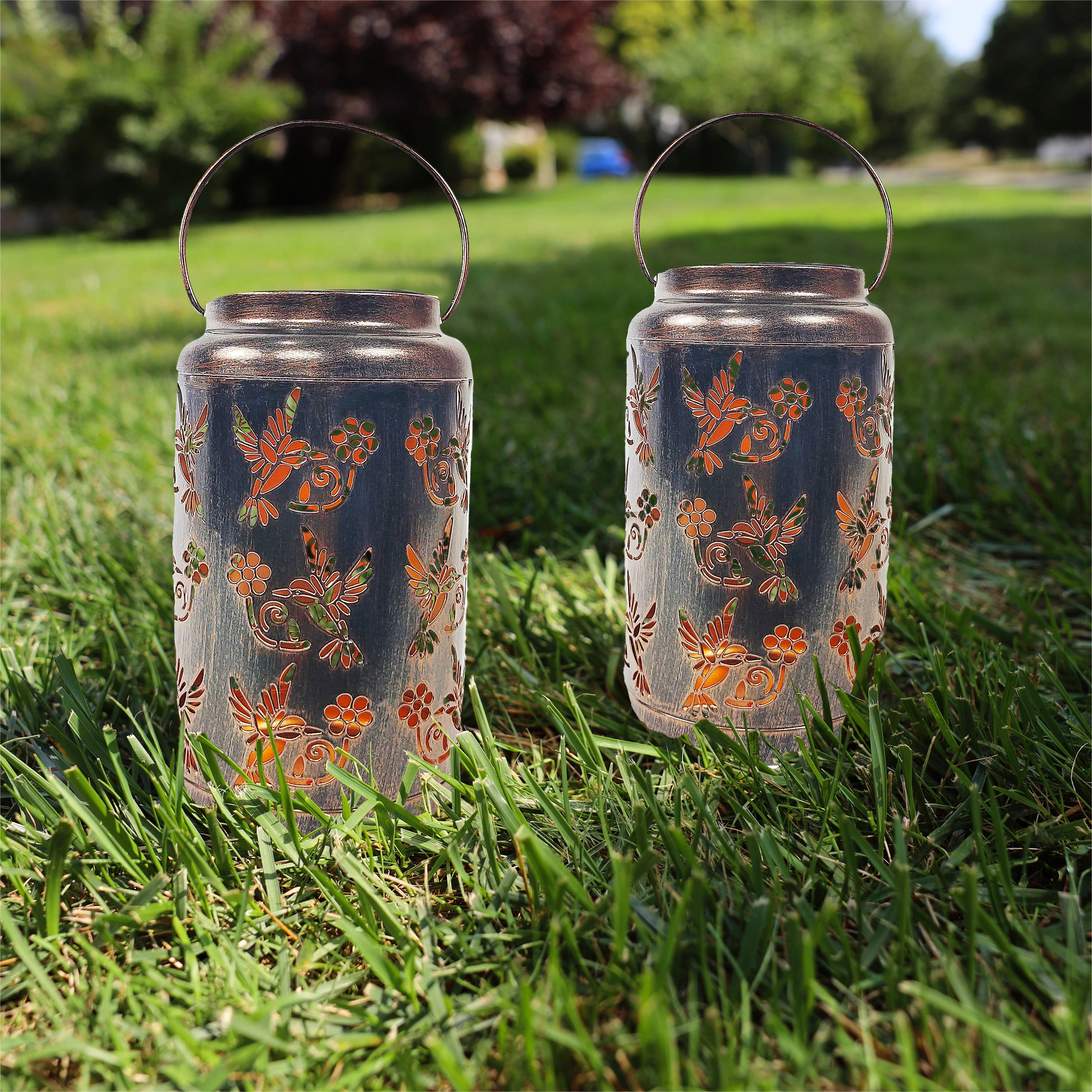 Set of 2 bronze LED lanterns on a lawn.