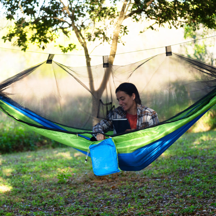 Woman sitting outside in the Bliss Hammocks 54-inch wide Mermaid-variation Camping Hammock with the mosquito net zippered shut.