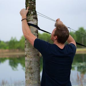 Man securing the mosquito net to a tree.
