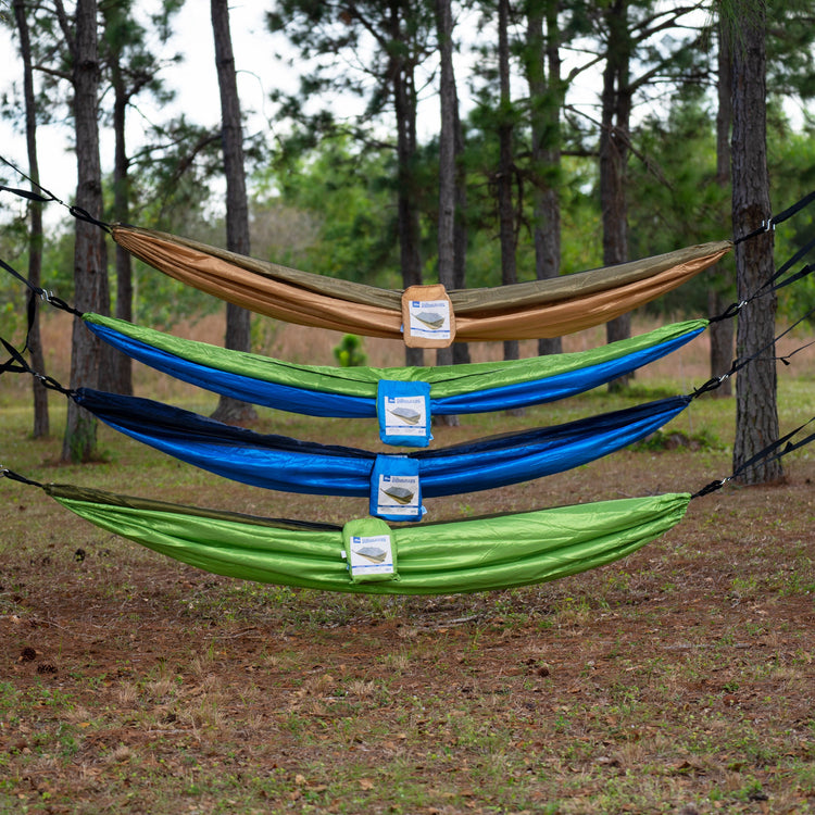 4 Bliss Hammocks Camping Hammocks of different variations hung above one another between two trees.