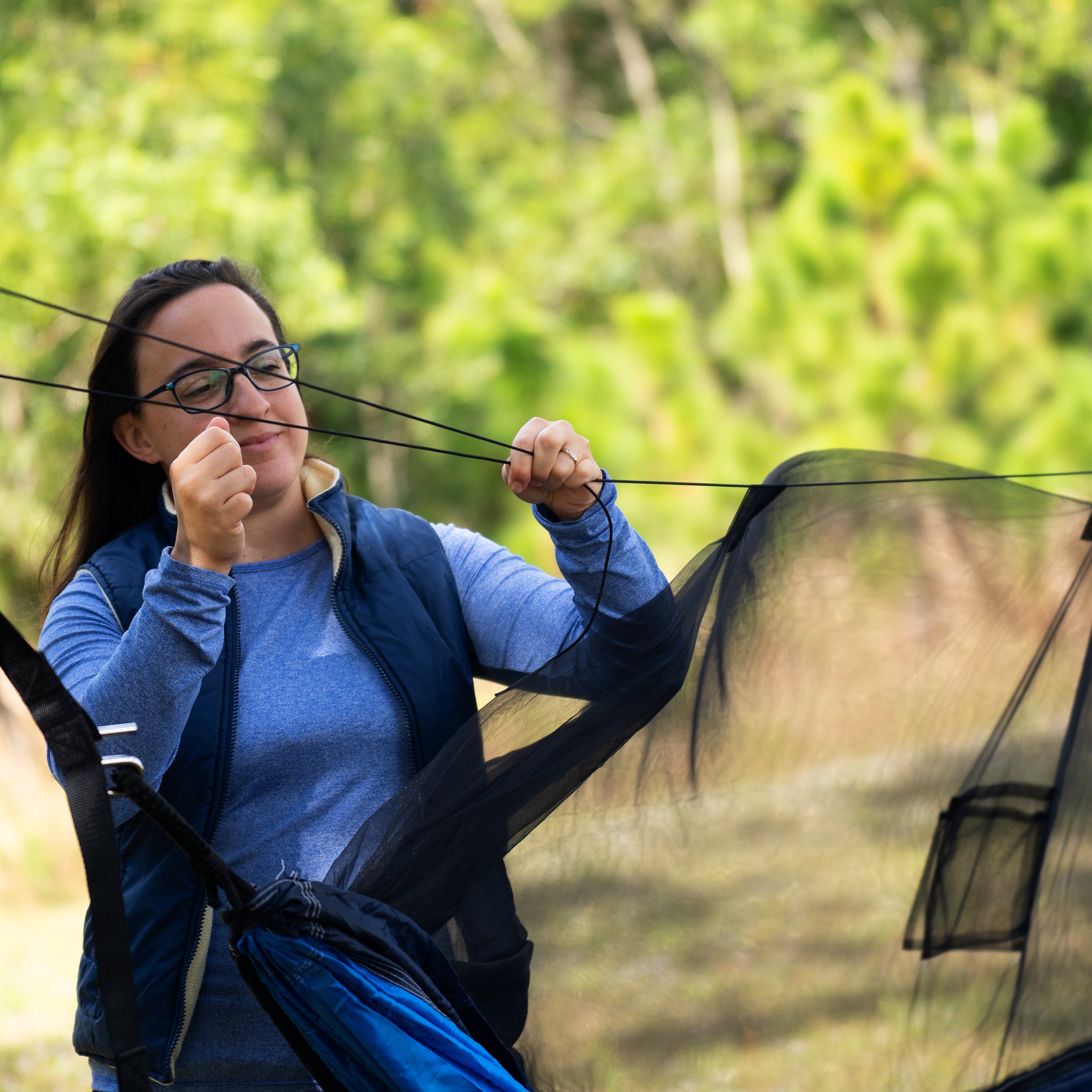 Woman securing the mosquito net to a tree.
