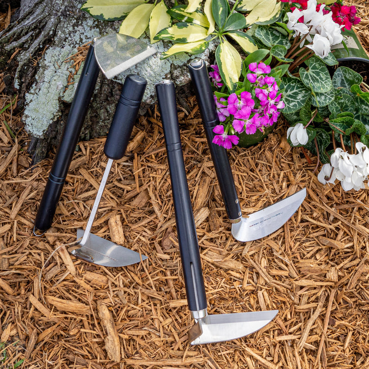 Nisaku garden hoes laying in mulch next to flowers.