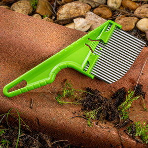 Nisaku Zassou Burush Tongari 3-inch Stainless Steel Angled Weeder outside next to rocks.