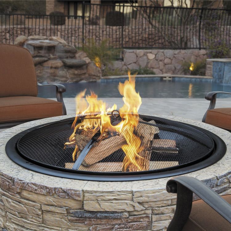 Fire going in the Sun Joe 28-Inch Classic Cast Stone Base, Wood Burning 24-Inch Fire Pit with patio chairs around it.