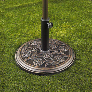Umbrella base with rose design holding an umbrella on grass.